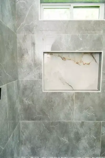 Beautiful shower with large format polish stone gray tiles and contrasted tile shower niche that will make your home the envy of your friends